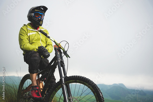 Fototapeta Naklejka Na Ścianę i Meble -  Portrait of a man aged on a mountain bike in the mountains in cloudy weather. Mountain bike concept