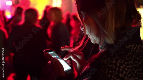 Young woman with smartphone texting message and sharing picture in social media on outdoor festival night party concert Party, holiday, celebration, nightlife and people concept.