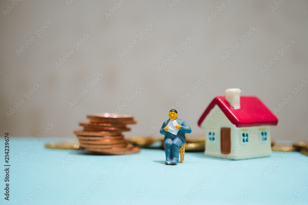 Miniature people, man sitting with stack coins and mini house using as job retirement and insurance concept Miniature people, man sitting with stack coins and mini house using as job retirement and insurance concept