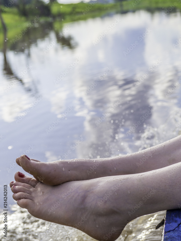 Lady feet floating above river from the boat