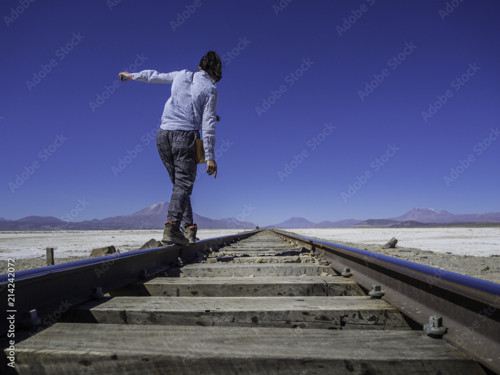 Woman traveler walking into the horizon on a train rail
