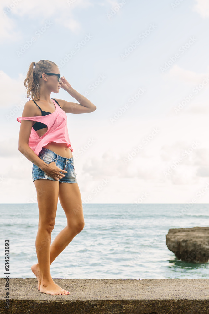 Pretty girl in summer outfit walk on pier, touch her fashion sunglasses and look forward. Sexy lady on sea beach sunset or ocean sunrise. Travel, explore, active yoga and meditation lifestyle concept. Pretty girl in summer outfit walk on pier, touch her fashion sunglasses and look forward. Sexy lady on sea beach sunset or ocean sunrise. Travel, explore, active yoga and meditation lifestyle concept.