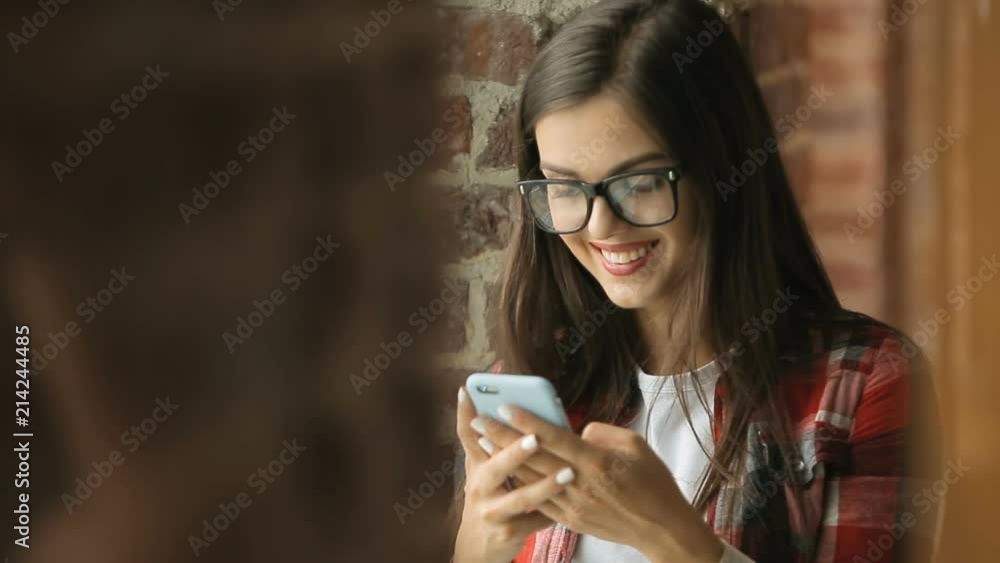 Young pretty woman smiles as reading a phone message, using gadget as relaxing in classically furnished cozy cottage Young pretty woman smiles as reading a phone message, using gadget as relaxing in classically furnished cozy cottage
