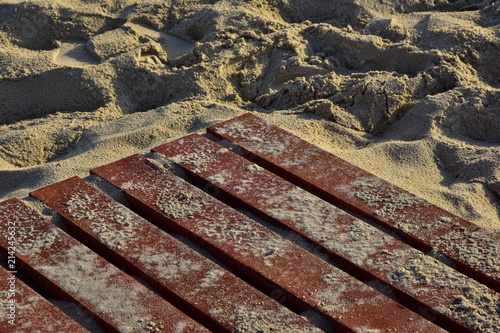 Background of sand on wooden red boards. Stairway of boards on a sandy beach