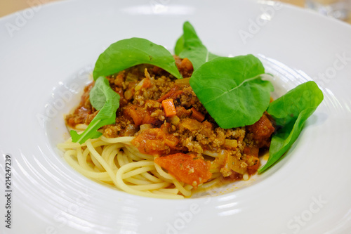 Spaghetti topped with ketchup, minced pork Put fresh tomatoes and sprinkle with rocket vegetables. Serve in a white plate.