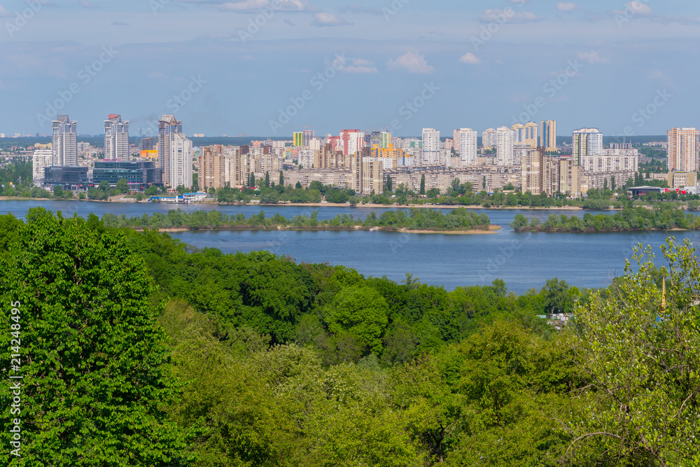 Panorama of multi-storey buildings on the shore of the Dnipro River under the blue sky. Kiev. Ukraine