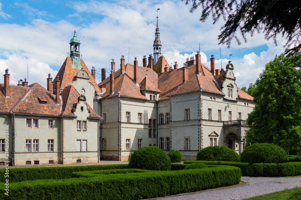An ancient beautiful castle with a tiled roof and a decorative park green area