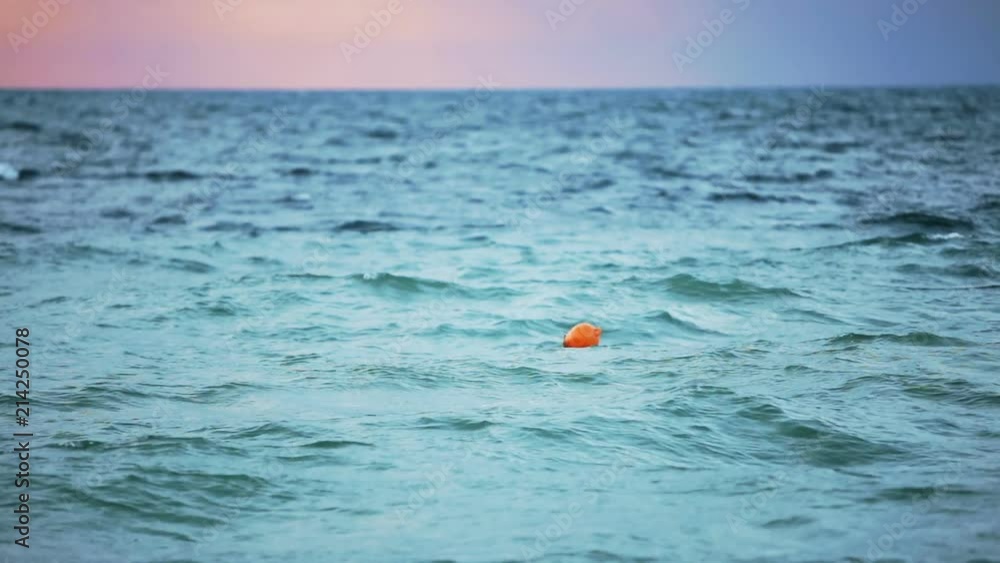 The orange buoy float floats in the sea. Overcast. The orange buoy float floats in the sea. Overcast.