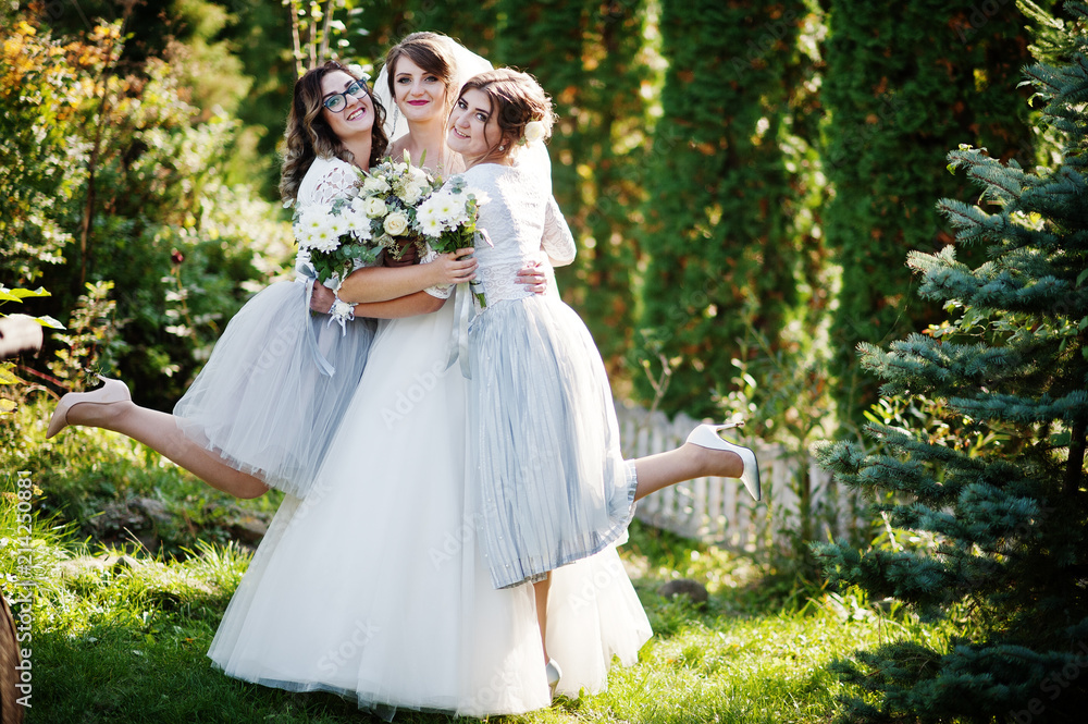 Happy bride posing with her bridesmaids outdoor with bouquets.