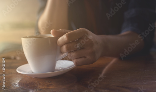 The hand of a woman holding a cup of coffee.