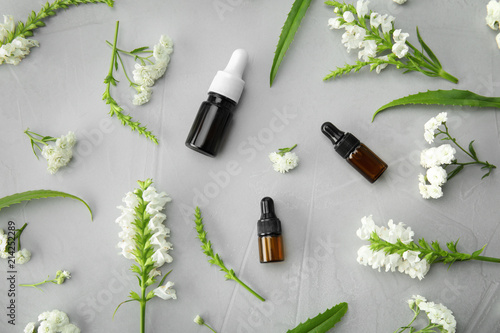 Flat lay composition with essential oils and flowers on grey background