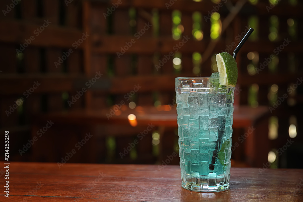 Glass with delicious cocktail and ice cubes on counter in bar Glass with delicious cocktail and ice cubes on counter in bar