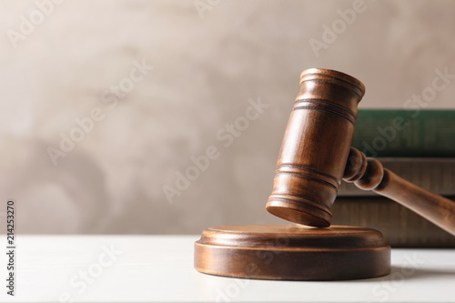 Wooden gavel and books on table against color background. Law concept