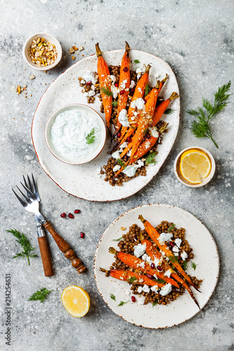 Roasted carrots lentil salad with feta, herb yogurt and dukkah on a light concrete background. Vegetarian food. Top view, flat lay photo