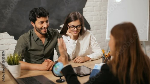 Joyful family couple having meeting with travel agent, talking about places around the world worth visiting, indoor shot in cozy small office