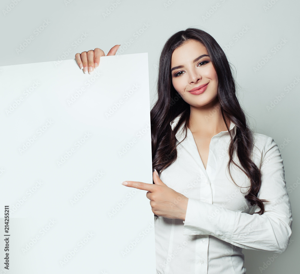 Smiling business woman holding white blank paper banner background and pointing. Confident student woman, business and education concept Smiling business woman holding white blank paper banner background and pointing. Confident student woman, business and education concept