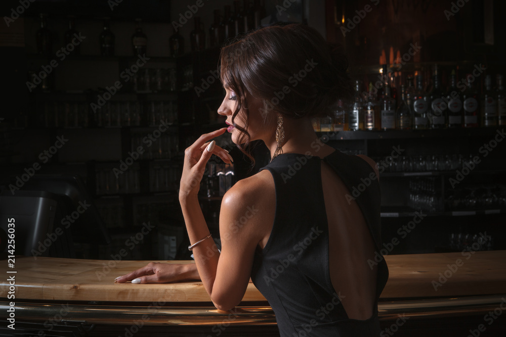 Fototapeta premium elegant lady in black dress, in restaurant at a bar