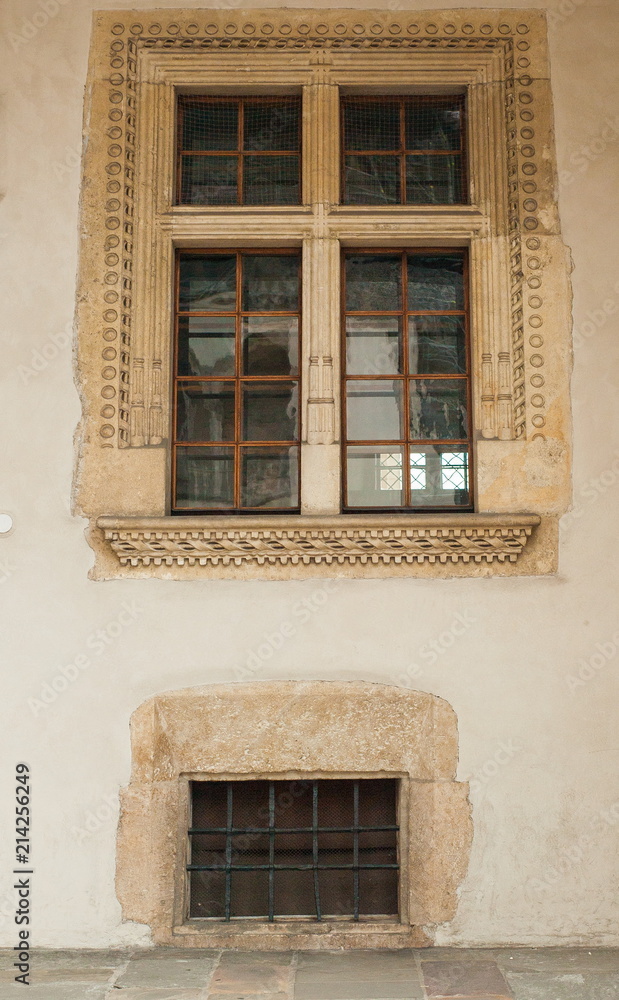 Obraz premium Part of the wall of an ancient castle with windows with bars. The wall of an ancient castle with windows as a texture for graphic design.