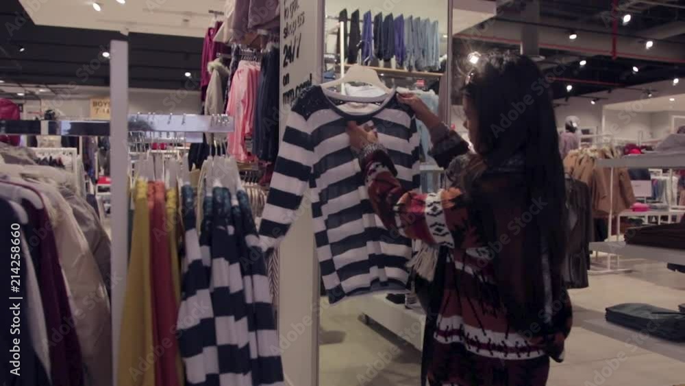 Asian woman scanning through a rack of clothes Asian woman scanning through a rack of clothes