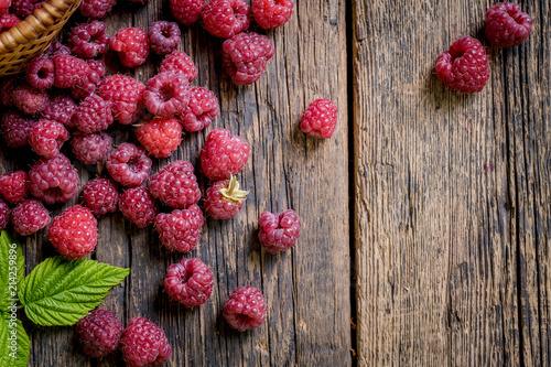 Ripe, freshly picked raspberries, on rustic wooden old table surface. Flat lay.