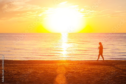 Fototapeta Naklejka Na Ścianę i Meble -  girl walking on the beach near the sea at sunset