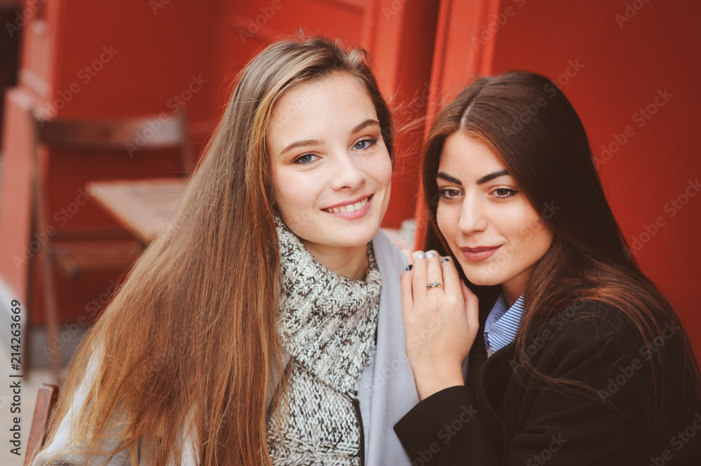 two happy girl friends talking and drinking coffee in autumn city in cafe. Meeting of good friends, young fashionable students with natural make up. two happy girl friends talking and drinking coffee in autumn city in cafe. Meeting of good friends, young fashionable students with natural make up.