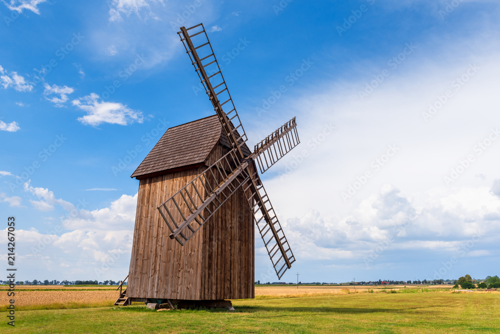 Old wooden windmill on field in summer day.