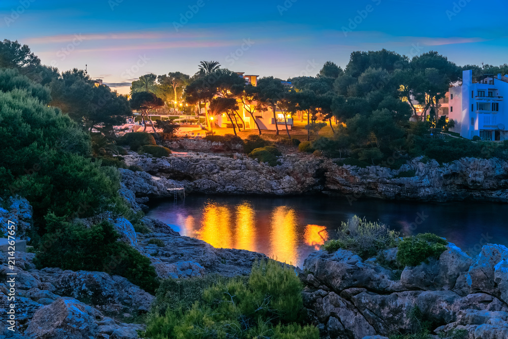 Night scene in Cala Dor region of Mallorca. Sea coast Punta Grosa illuminated by light in evening,