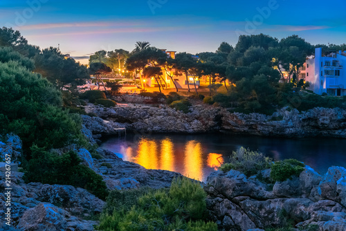Night scene in Cala Dor region of Mallorca. Sea coast Punta Grosa illuminated by light in evening, photo