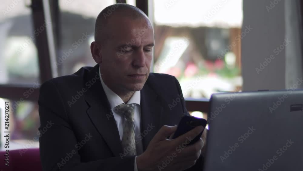 Businessman using his phone sitting at table in cafe at lunch Businessman using his phone sitting at table in cafe at lunch