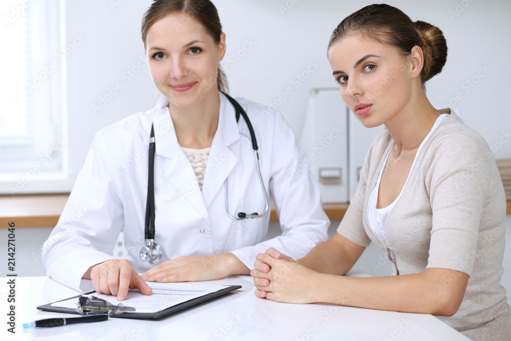 Doctor and patient having a pleasure talk while sitting at the desk at hospital office. Healthcare and medicine concept Doctor and patient having a pleasure talk while sitting at the desk at hospital office. Healthcare and medicine concept