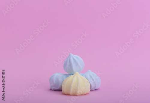 Several multicolored meringues on a pink background
