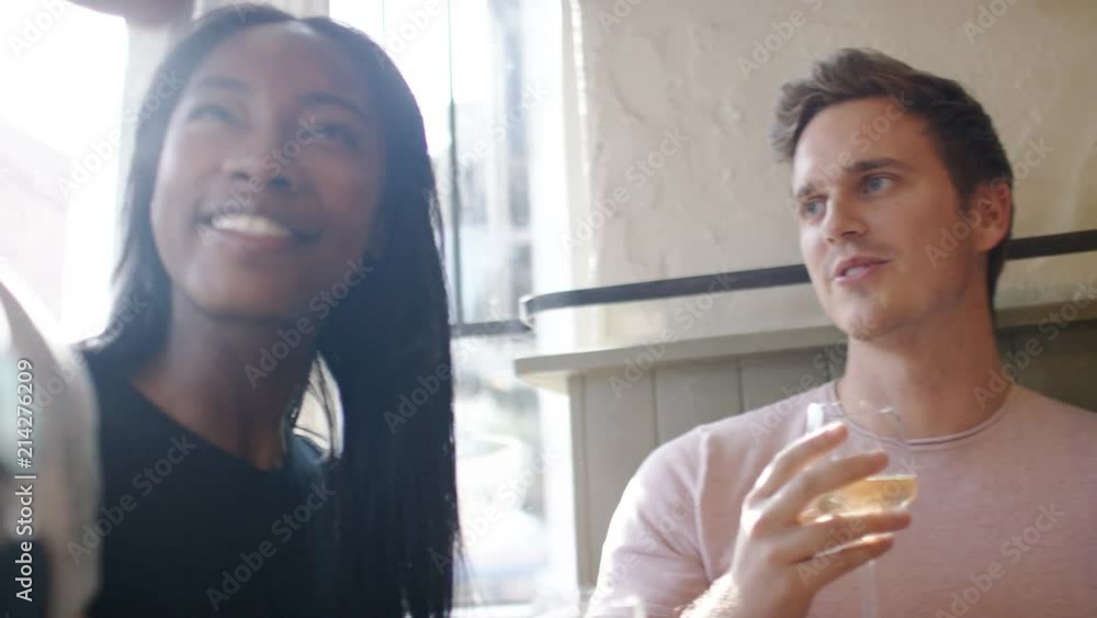 Two young couples in a wine bar having a cheerful conversation with sun flare Two young couples in a wine bar having a cheerful conversation with sun flare