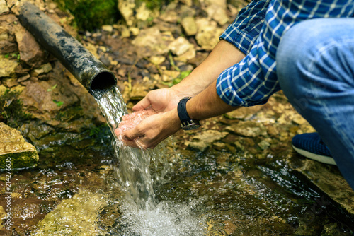 Male hands typing in her hands clean spring water