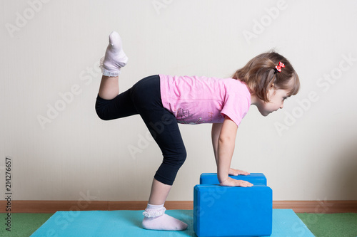 little girl, 3 years old. doing yoga with cubes