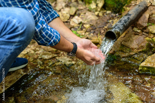 A man drinks from the hands of clean water from an underground source