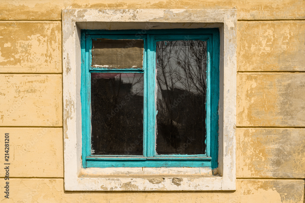 Old window in an abandoned house with blue wooden frame