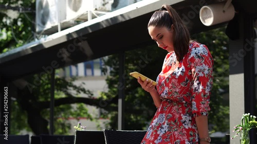 Beautiful girl in red dress, with flower pattern on the terace, outdoor in business centr. photo