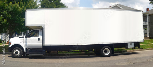 Side view of long white moving van parked on residential street. photo