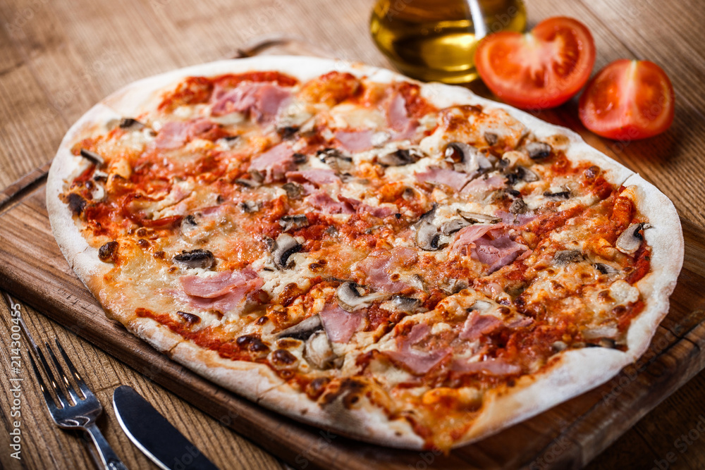 Pizza with ham, cheese, mushrooms and tomato sauce on wooden rustic table. Top view.