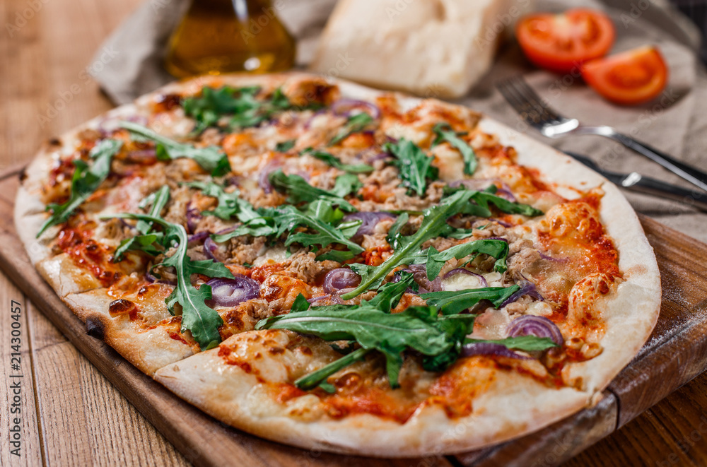 Pizza with chicken, arugula, cheese and onions on wooden rustic table. Top view.