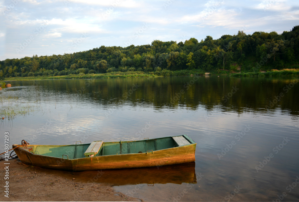 old wooden boat on the river bank. picturesque water landscape.calm and relaxing summer evening