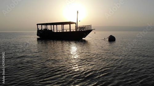 Schilderij op canvas Sun silhouetting a ship on the Sea of Galilee