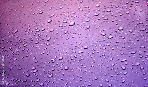 large and small drops of water on a violet bright background