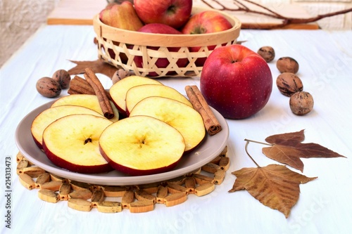 Round sliced apple with honey, fall leaves and nuts, on a veranda table, autumn still life. 