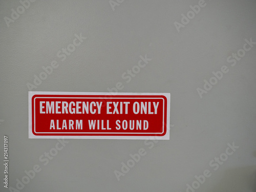 Emergency exit only, alarm will sound sign posted on a white door