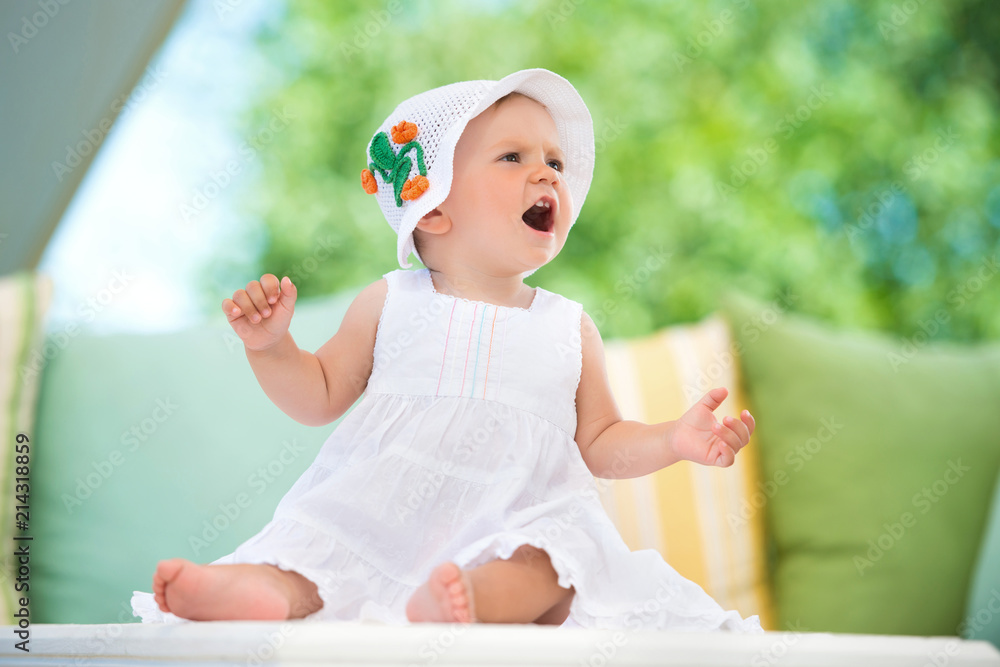 Cute little girl in a dress sits in pillows, smiling happily Cute little girl in a dress sits in pillows, smiling happily