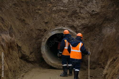 Worker in safety uniform install concrete precast pipe drainage under ground road .