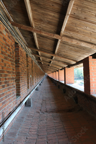 monastic wall of red brick with columns and wooden roof