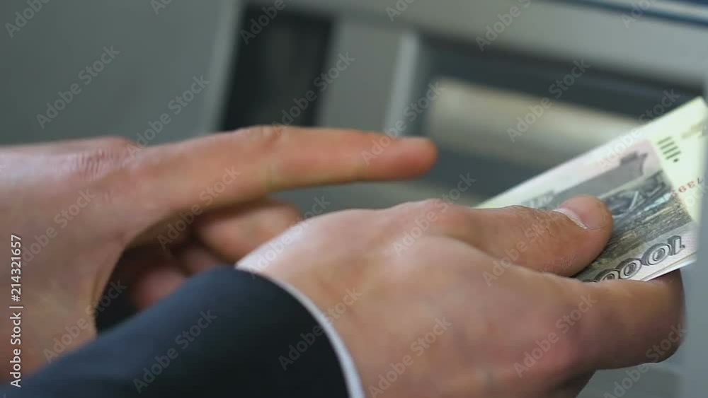 Hands of businessman counting Russian rubles near ATM, putting money in wallet Hands of businessman counting Russian rubles near ATM, putting money in wallet
